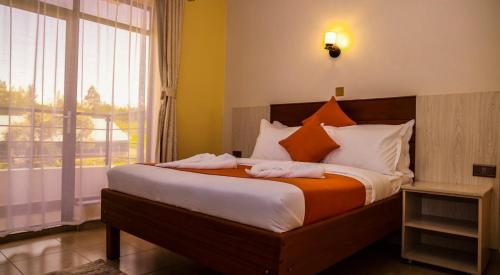 a bedroom with a large bed with orange and white pillows at Sanel Hotel in Naivasha