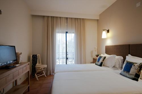 a hotel room with two beds and a television at Hotel Parque das Laranjeiras in Vilamoura