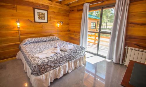 a bedroom with a bed in a log cabin at Del Milagro Cabañas & Posada in Villa General Belgrano
