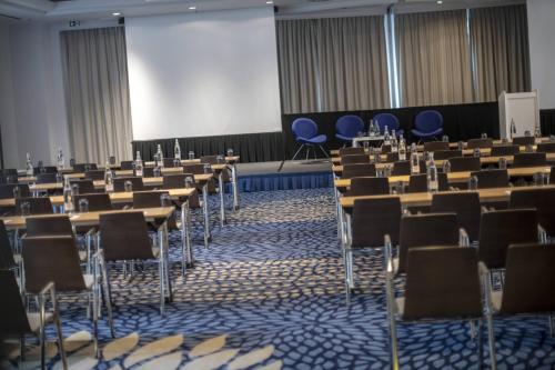 a room with rows of tables and blue chairs at Renaissance Brussels Hotel in Brussels