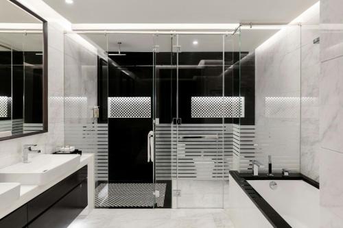 a bathroom with a shower and a sink and a tub at Renaissance Business Bay Hotel, Dubai in Dubai