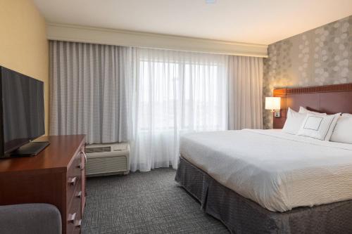 a hotel room with a bed and a flat screen tv at Courtyard Des Moines West-Jordan Creek in West Des Moines