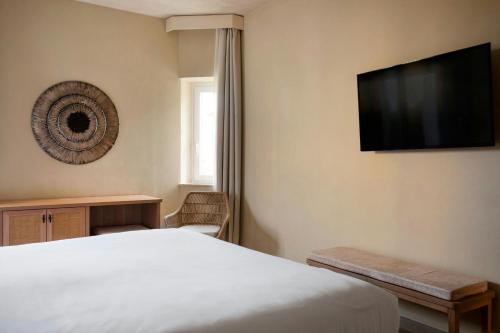 a bedroom with a bed and a flat screen tv at Mangia's Brucoli, Sicily, Autograph Collection in Brucoli