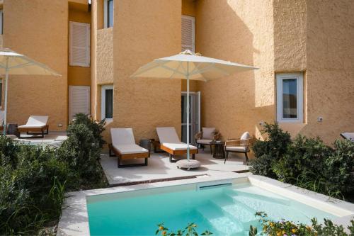 a swimming pool with chairs and umbrellas next to a building at Mangia's Brucoli, Sicily, Autograph Collection in Brucoli