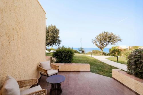 a patio with chairs and a table and a sidewalk at Mangia's Brucoli, Sicily, Autograph Collection in Brucoli