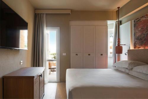 a bedroom with a bed and a door to a balcony at Mangia's Brucoli, Sicily, Autograph Collection in Brucoli