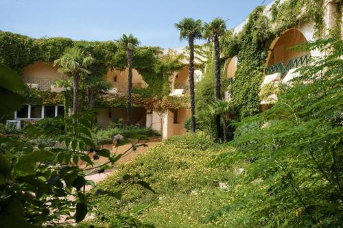 a building covered in ivy with trees and bushes at Mangia's Brucoli, Sicily, Autograph Collection in Brucoli