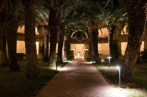 a hallway with palm trees in front of a building at Mangia's Brucoli, Sicily, Autograph Collection in Brucoli