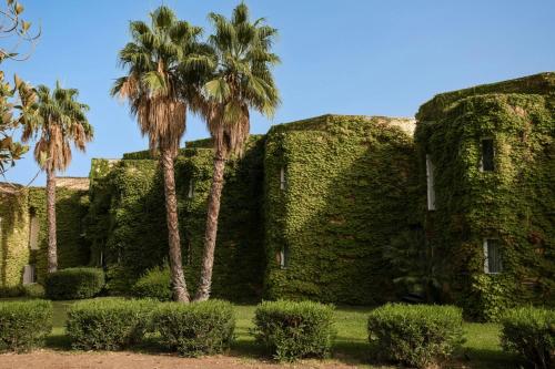 an old building with palm trees in front of it at Mangia's Brucoli, Sicily, Autograph Collection in Brucoli