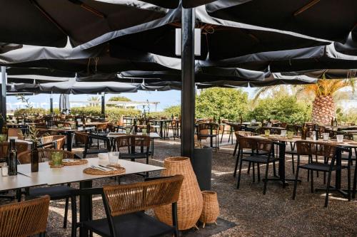 a restaurant with tables and chairs under a large umbrella at Mangia's Brucoli, Sicily, Autograph Collection in Brucoli