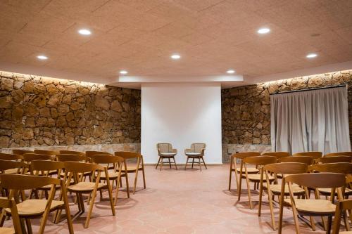 a room with rows of chairs and a stone wall at Mangia's Brucoli, Sicily, Autograph Collection in Brucoli