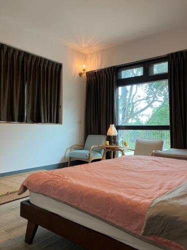 a bedroom with a bed and a window and chairs at Greenville Maioli in Tongxiao