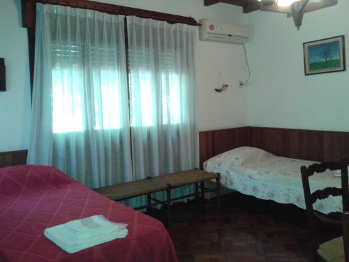 a bedroom with two beds and a window with curtains at Casa Suiza in Luis Guillón