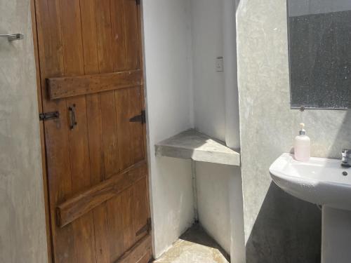 a bathroom with a wooden door and a sink at Kitekuda Kite Resort in Vannativillu