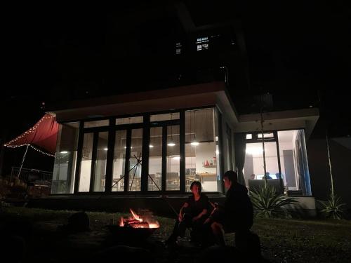 a man and woman sitting in front of a house at night at Greenville Maioli in Tongxiao