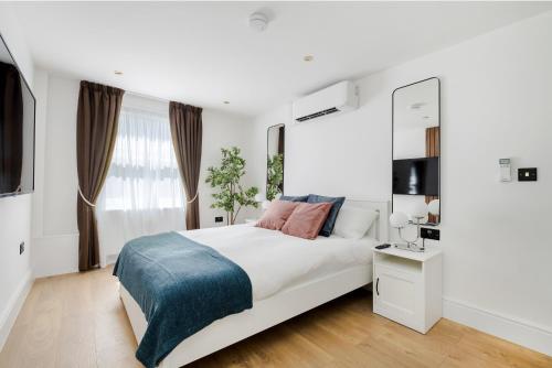 Un dormitorio blanco con una cama grande y una ventana. en Luxury Apartment in Marylebone, en Londres