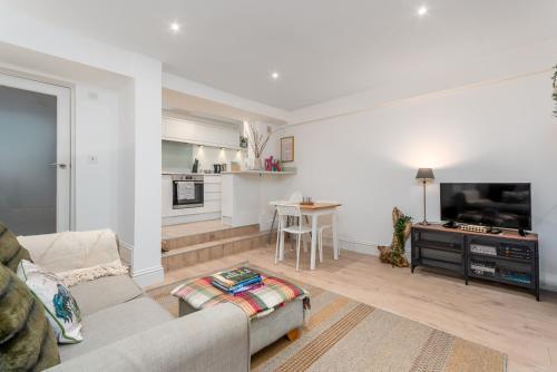 a living room with a couch and a tv and a kitchen at Clarendon Place - Stunning 1BD in Leamington Spa! in Leamington Spa