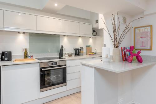 a white kitchen with white cabinets and appliances at Clarendon Place - Stunning 1BD in Leamington Spa! in Leamington Spa