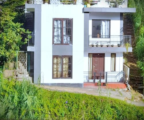 a white house with a porch and a balcony at Villa White Orchid in Hatton