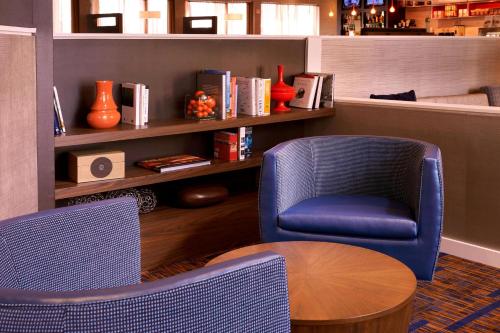 a room with two chairs and a table and a shelf at Courtyard Dayton South Mall in Miamisburg