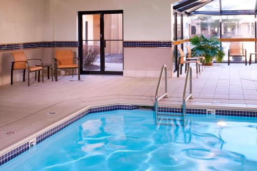 a pool in a hotel with chairs and a table at Courtyard Dayton South Mall in Miamisburg