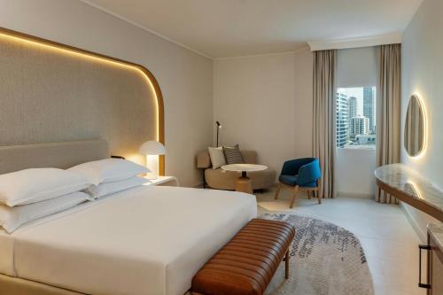 a bedroom with a large white bed and a living room at Sheraton Jumeirah Beach Resort in Dubai
