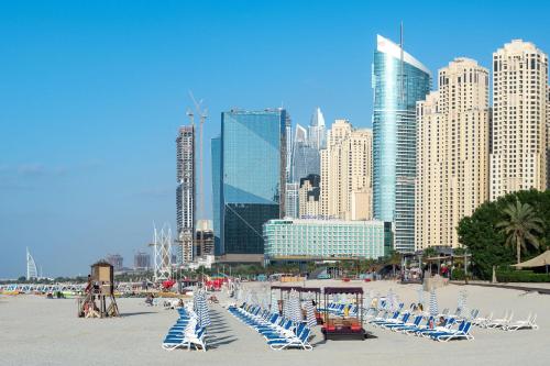 a beach with lounge chairs and a city skyline at Sheraton Jumeirah Beach Resort in Dubai