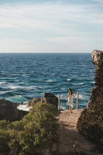 a woman standing on a pier looking at the ocean at Almare, a Luxury Collection Resort, Isla Mujeres, Adult All-Inclusive in Isla Mujeres