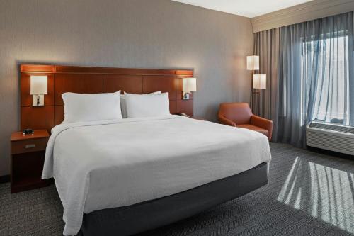 a hotel room with a large bed and a chair at Courtyard Long Beach Airport in Long Beach