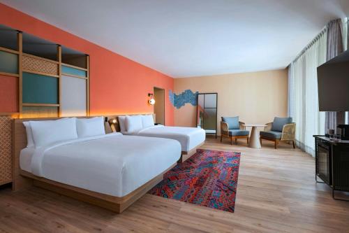 a hotel room with two beds and a table at Aloft Playa del Carmen in Playa del Carmen