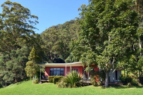 a house in the middle of a field with trees at The Heavens Mountain Escape in Kangaroo Valley