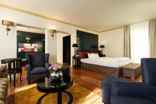 a hotel room with a bed and chairs and a table at Hotel Würzburger Hof **** in Würzburg