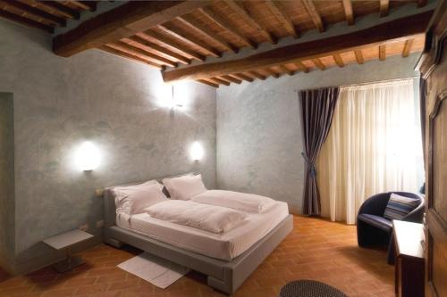 a bedroom with a white bed and a chair at Relais Casanova in San Gusmè