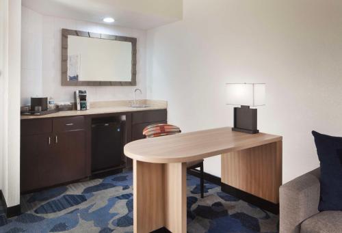 棕榈滩花园Embassy Suites by Hilton Palm Beach Gardens PGA Boulevard的酒店客房配有书桌和带台灯的桌子。