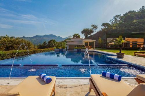 a swimming pool with two chairs in front of a house at La Quinta by Wyndham Poza Rica in Poza Rica de Hidalgo