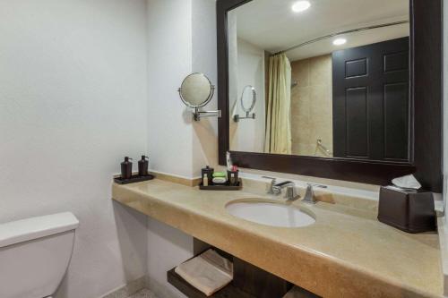 a bathroom with a sink and a toilet and a mirror at La Quinta by Wyndham Poza Rica in Poza Rica de Hidalgo