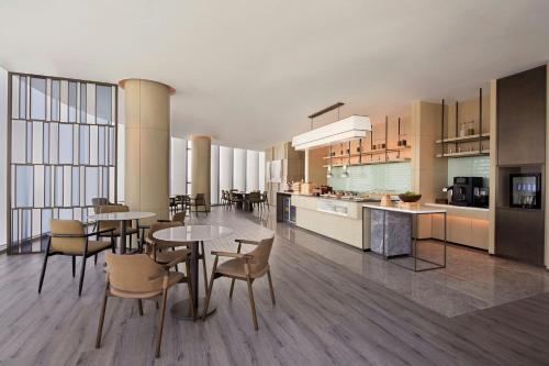 an open kitchen and dining room with tables and chairs at Courtyard by Marriott Hangzhou Xihu in Hangzhou