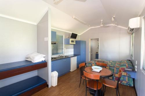 Habitación pequeña con mesa, cama y cocina en Ivanhoe Resort, en Kununurra