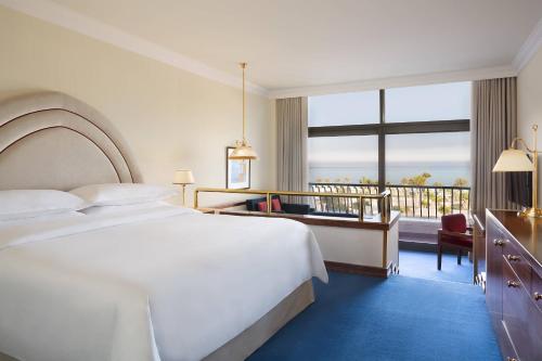a hotel room with a bed and a balcony at Sheraton Grand Doha Resort & Convention Hotel in Doha