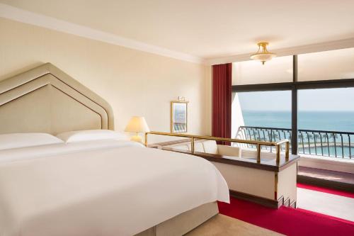 a bedroom with a large bed and a balcony at Sheraton Grand Doha Resort & Convention Hotel in Doha