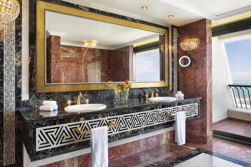 a bathroom with two sinks and a large mirror at Sheraton Grand Doha Resort & Convention Hotel in Doha