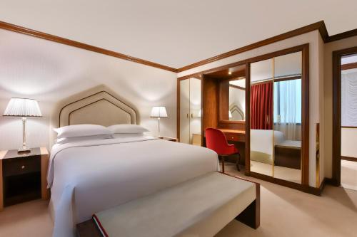 a bedroom with a large white bed and a desk at Sheraton Grand Doha Resort & Convention Hotel in Doha