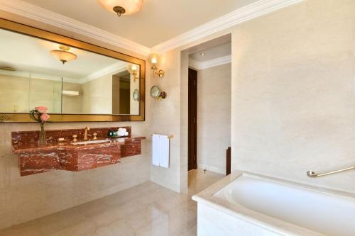 a bathroom with a tub and a large mirror at Sheraton Grand Doha Resort & Convention Hotel in Doha
