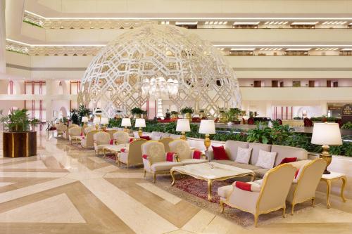 a lobby with a line of couches and a chandelier at Sheraton Grand Doha Resort & Convention Hotel in Doha