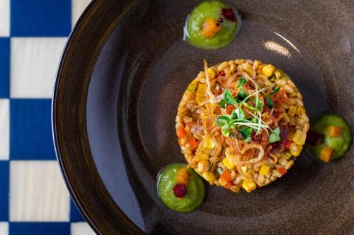 a plate of food with corn salsa and green peppers at Sheraton Grand Doha Resort & Convention Hotel in Doha