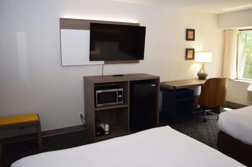 a hotel room with a bed and a desk with a television at Comfort Inn & Suites Syracuse-Carrier Circle in East Syracuse