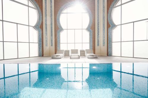 a pool with chairs and windows in a room with water at Tilal Riyadh in Riyadh