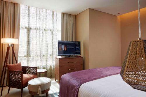 a hotel room with a bed and a flat screen tv at Tilal Riyadh in Riyadh