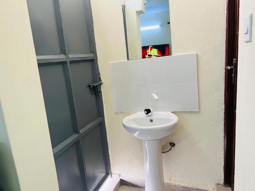 a bathroom with a white sink next to a door at Kiv haven homes, 1 bedroom old ferry in Kilifi