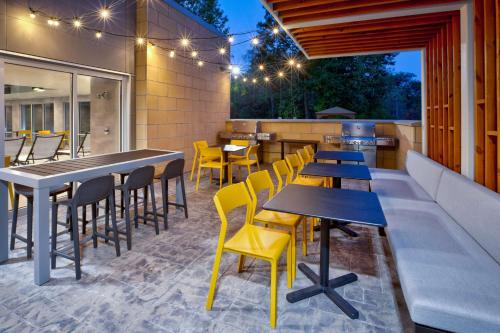a restaurant with tables and yellow chairs on a patio at Home2 Suites By Hilton Grand Rapids Northeast in Grand Rapids